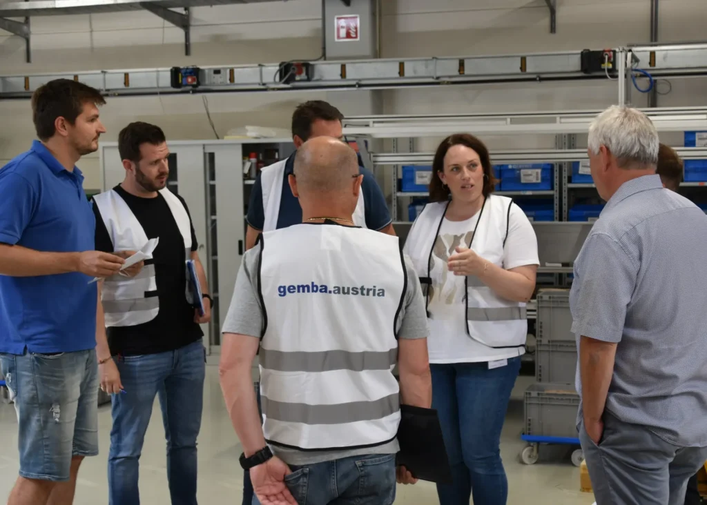 5S Methode in der Produktion: Team führt eine Shopfloor-Besprechung durch und diskutiert nachhaltige Verbesserungen am Arbeitsplatz.